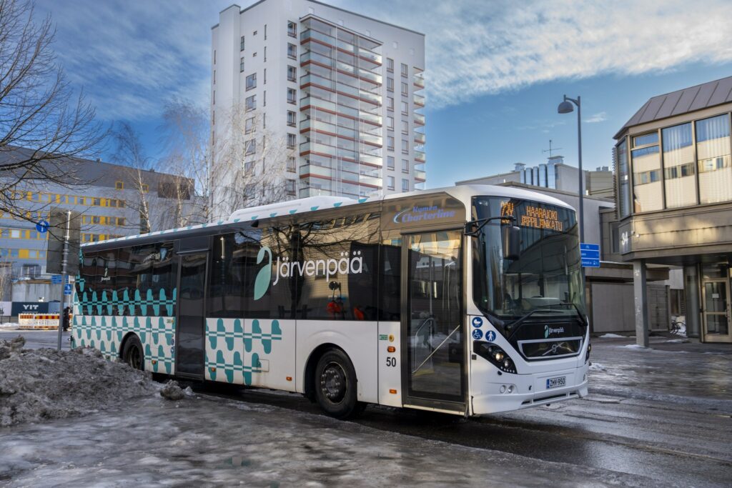 Järvenpään kaupungin logolla varustettu linja-auto ajamassa kaupungin keskustassa.